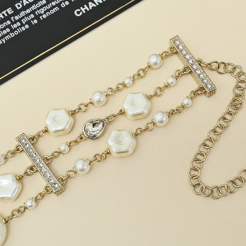 Gold-tone charm bracelet with pearl strands, white shell links, and crystal bar charm stations