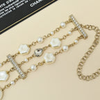 Gold-tone charm bracelet with pearl strands, white shell links, and crystal bar charm stations