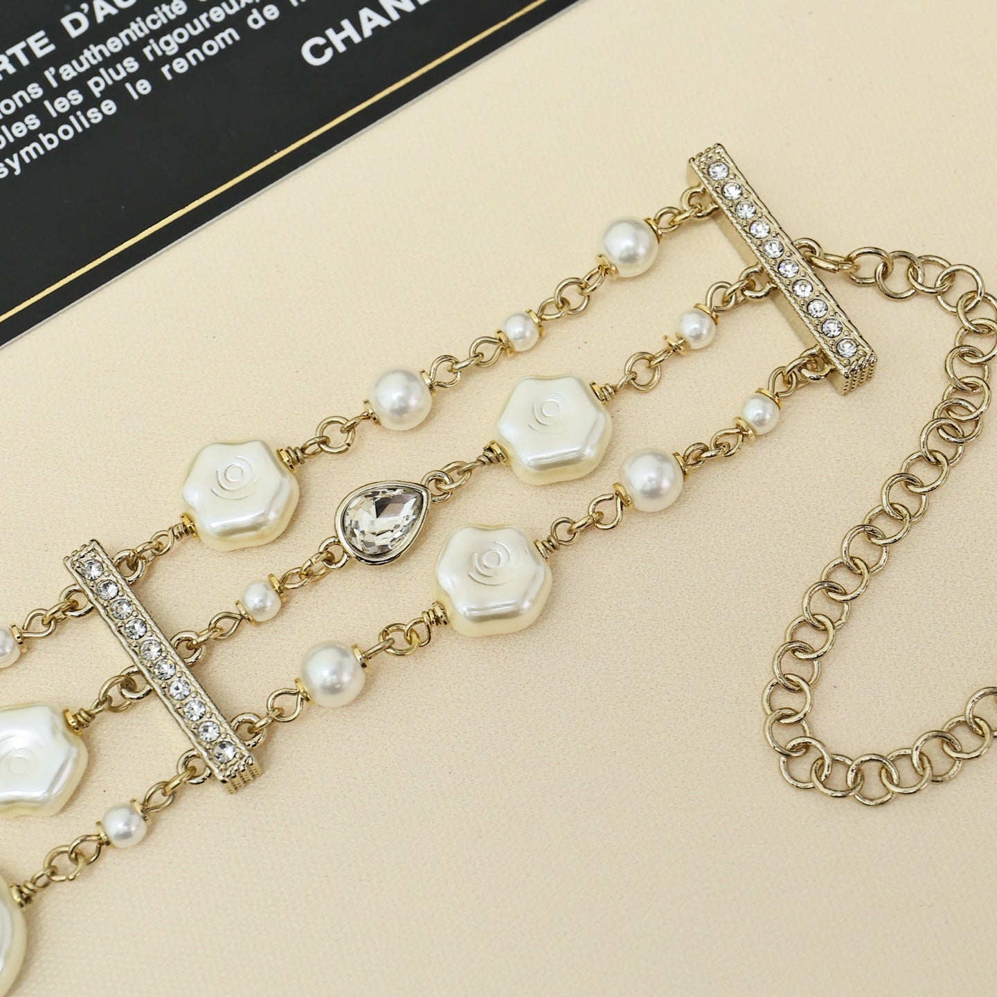 Gold-tone charm bracelet with pearl strands, white shell links, and crystal bar charm stations