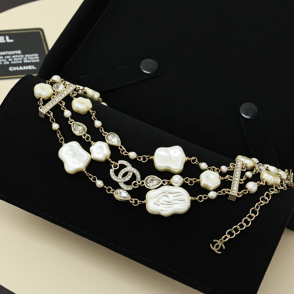 Charm bracelet with gold-tone chain, white shell charms, pearls, and crystal pavé bar accents