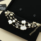Charm bracelet with gold-tone chain, white shell charms, pearls, and crystal pavé bar accents