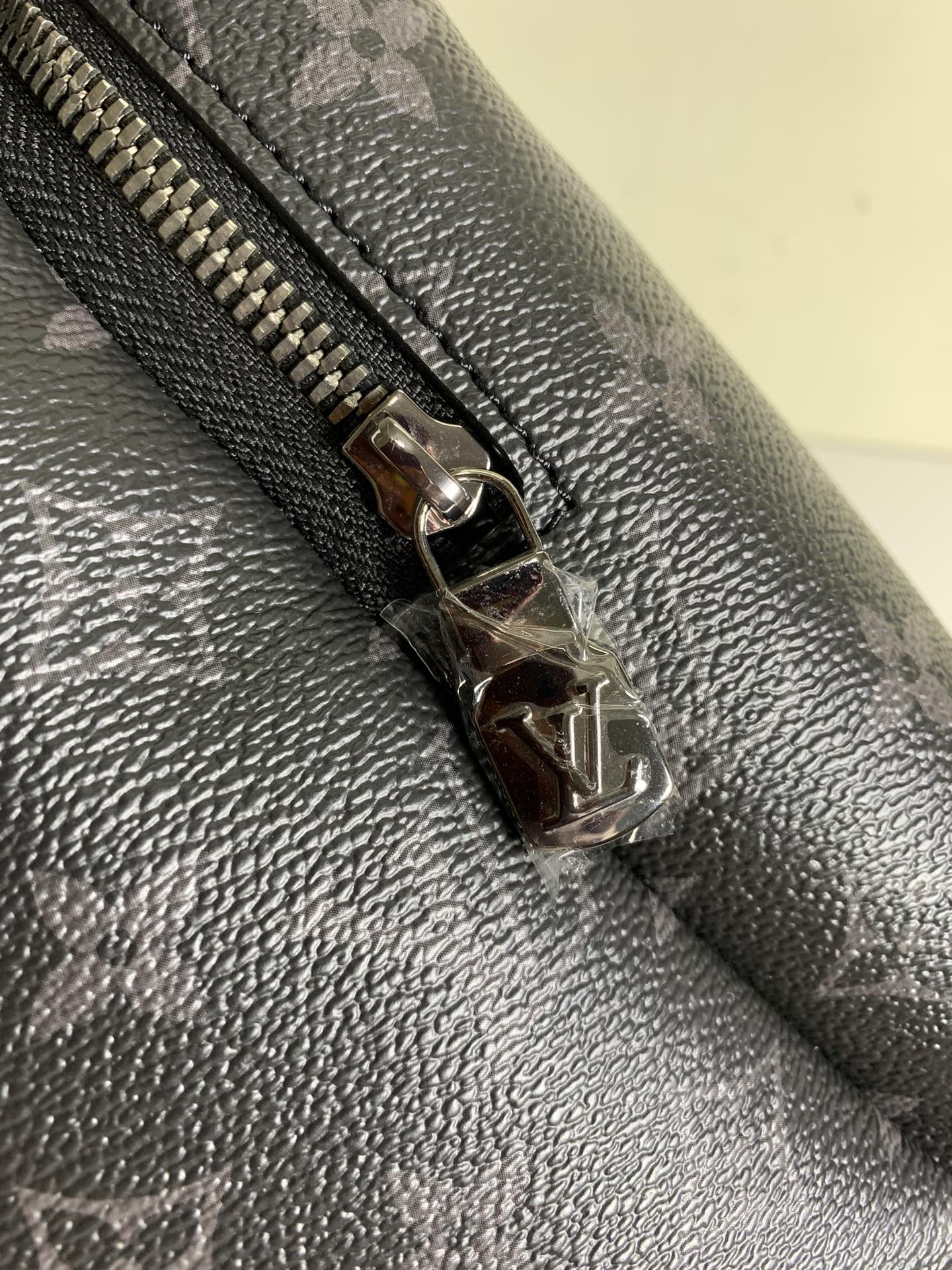 Louis Vuitton monogram backpack zipper pull, silver-tone hardware on leather