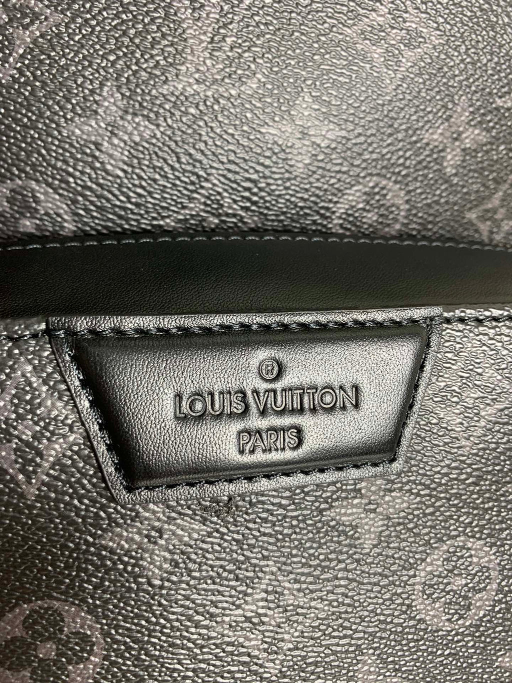 Louis Vuitton Paris leather label on dark monogram bag, textured surface
