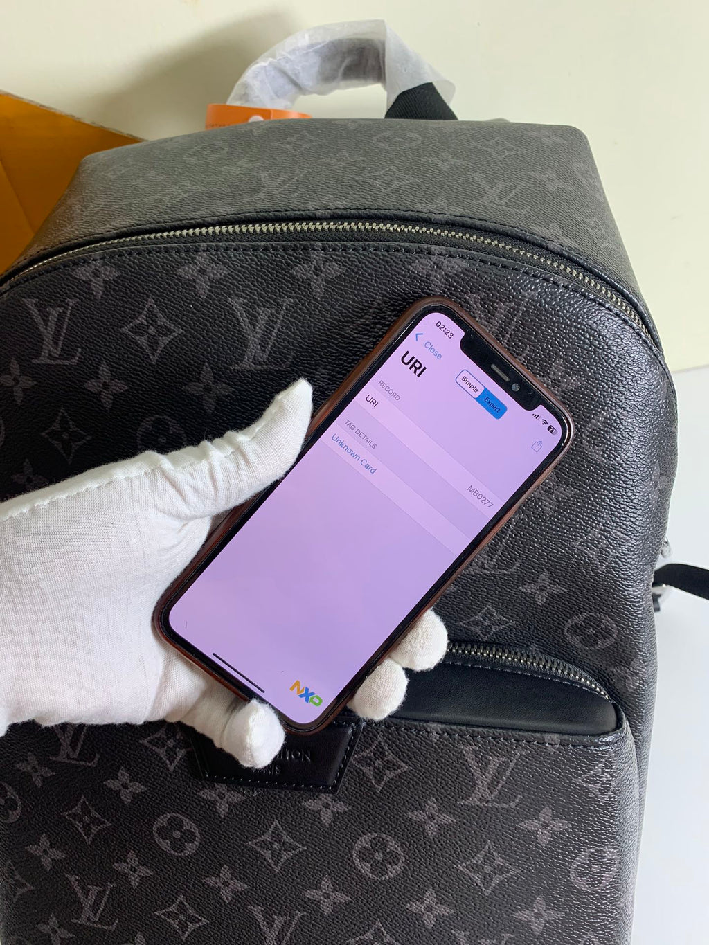 Louis Vuitton monogram backpack, front pocket zip with smartphone on surface