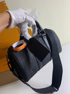 Louis Vuitton bag carried by the handle with dark textured leather and strap