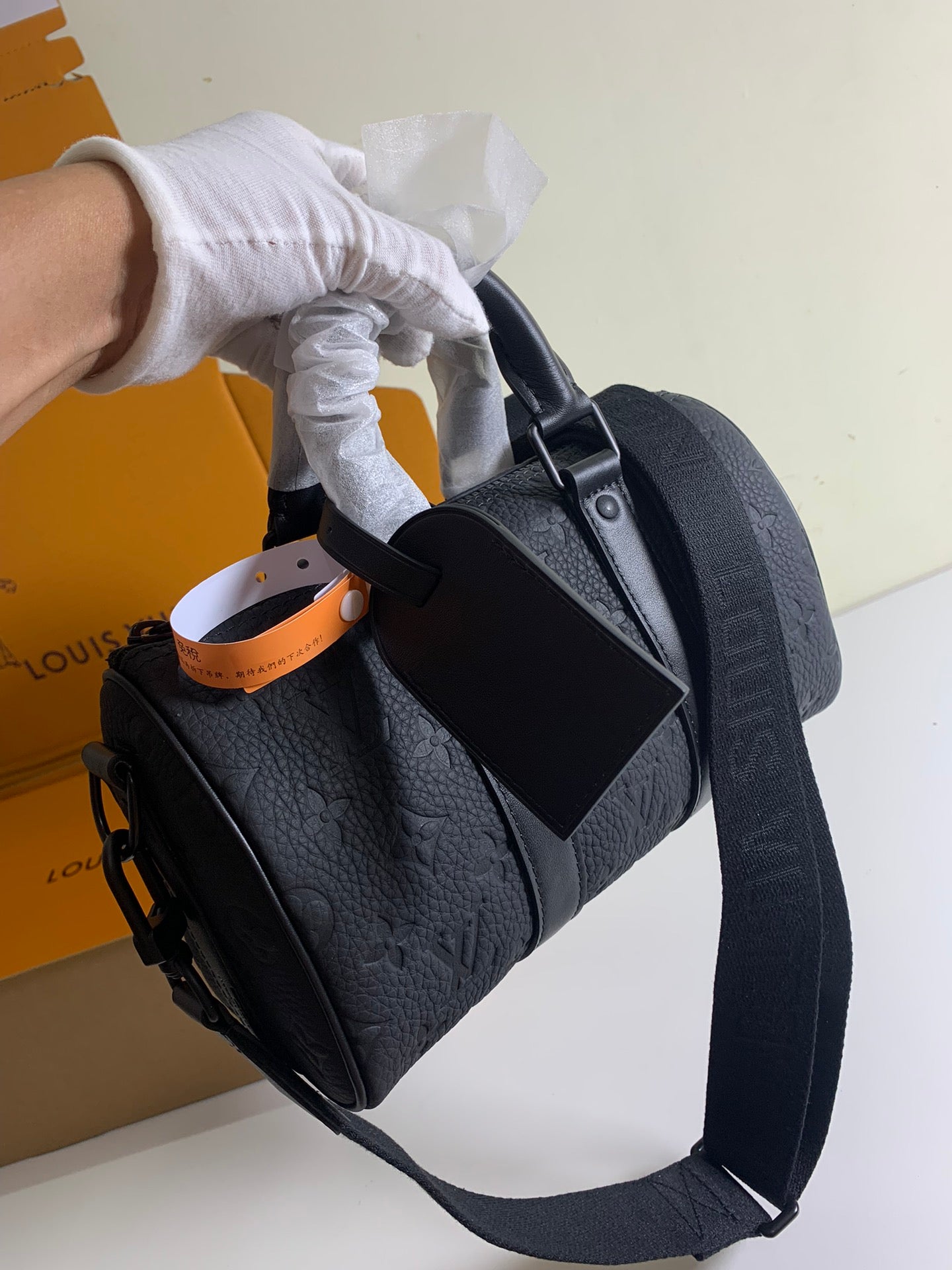 Louis Vuitton bag carried by the handle with dark textured leather and strap