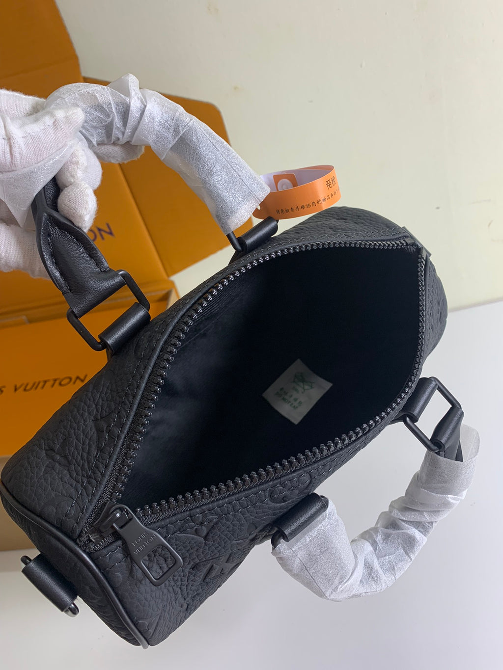 Louis Vuitton dark monogram bag with front zipper and pebble-leather texture