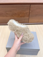 Single beige faux-fur slide sandal held in hand, white insole visible