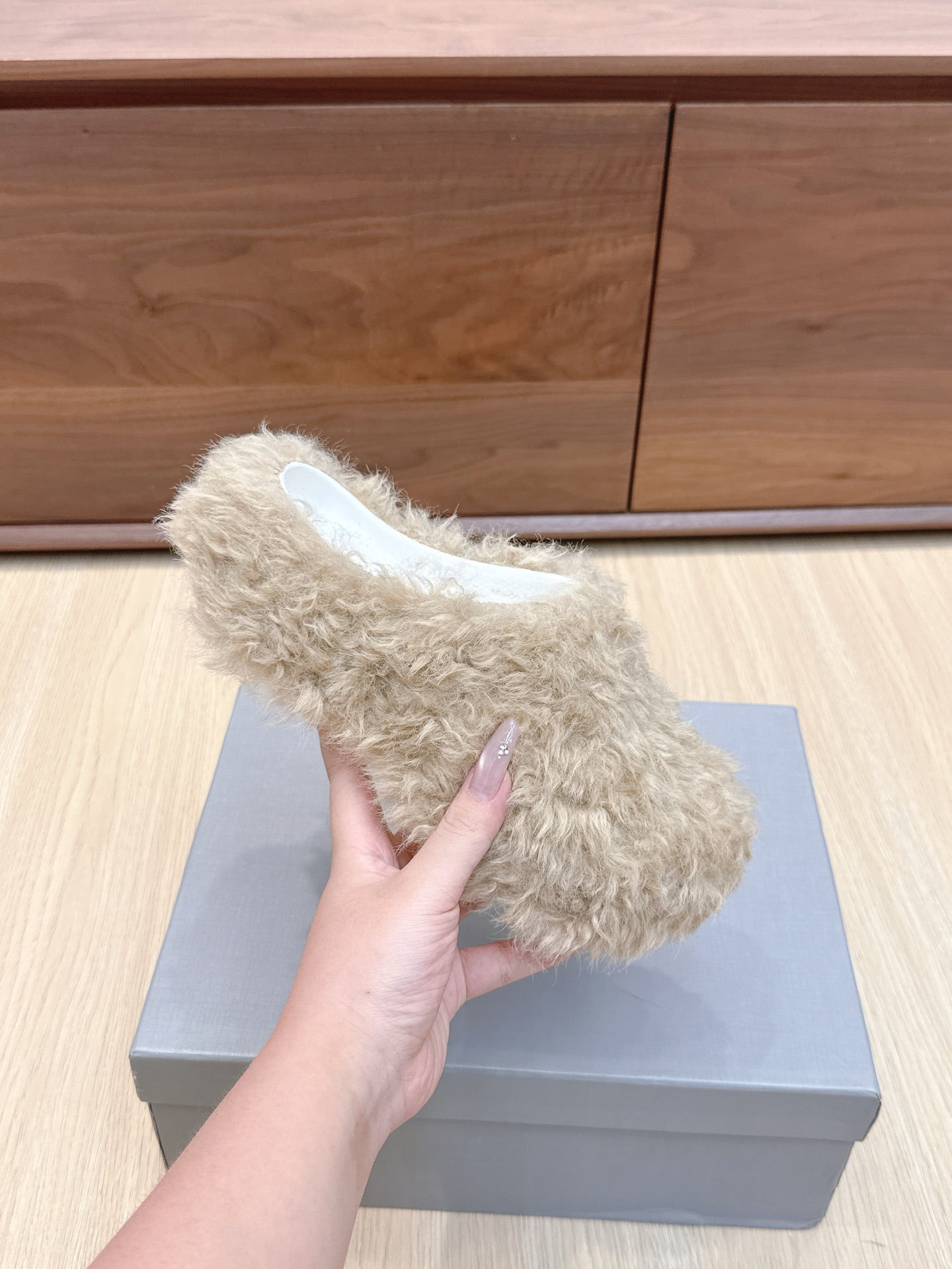 Single beige faux-fur slide sandal held in hand, white insole visible