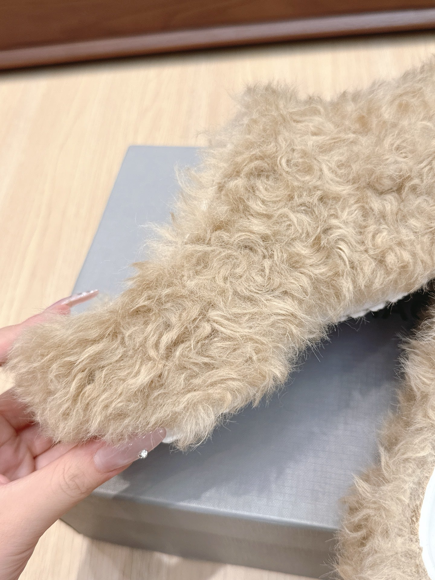 Beige faux-fur slide sandal upper, side profile held above box