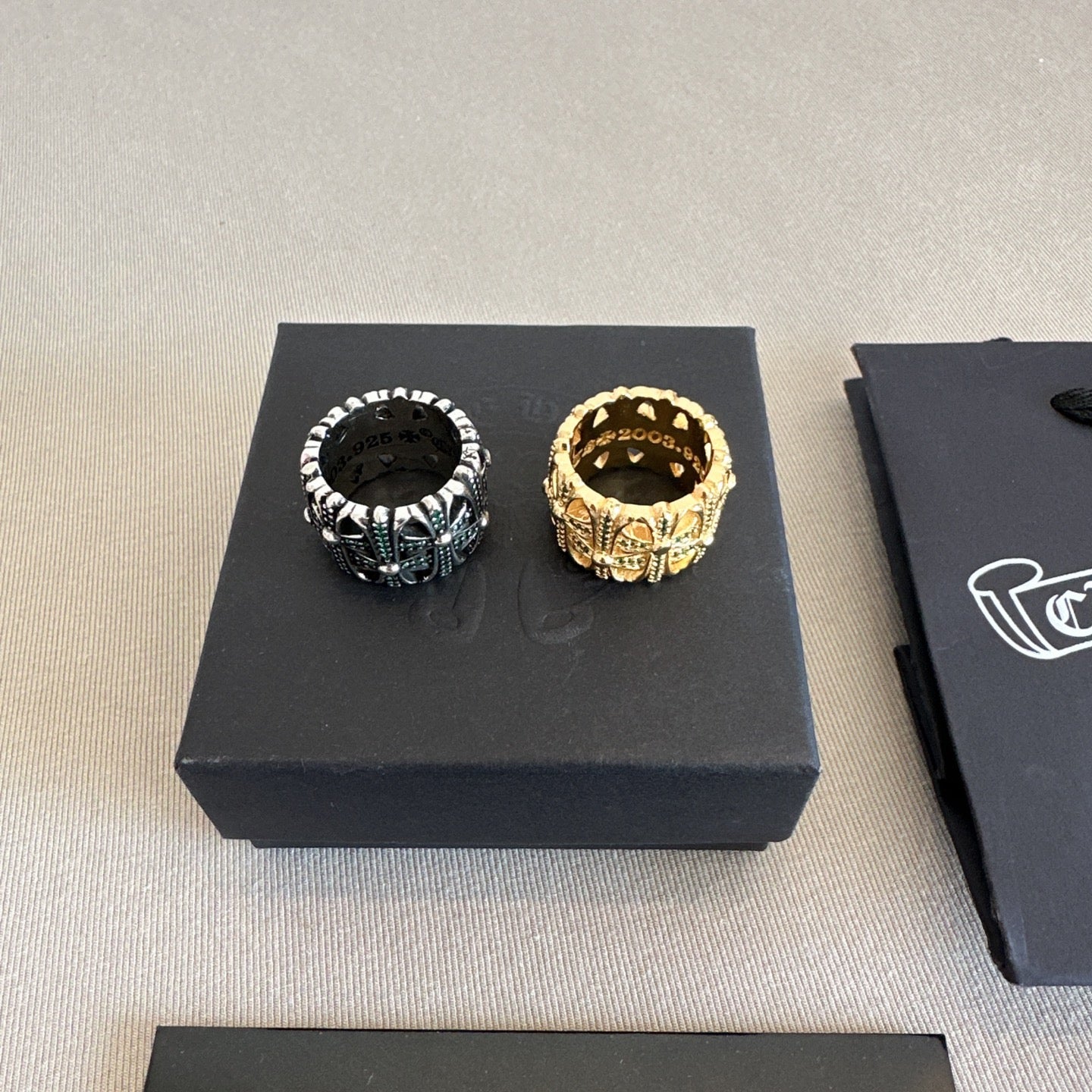 Chrome accessories pair of rings on a black box top, black ring and gold ring