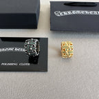 Chrome accessories rings beside polishing cloth card, black ring with green stones and gold ring