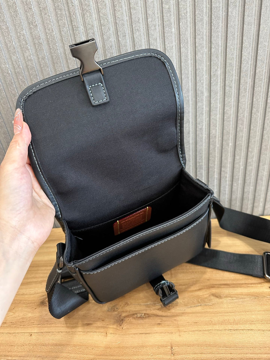 Black flap crossbody bag open view showing interior pocket and adjustable strap
