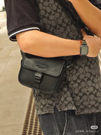 Black crossbody bag worn on body, front flap with buckle and adjustable strap