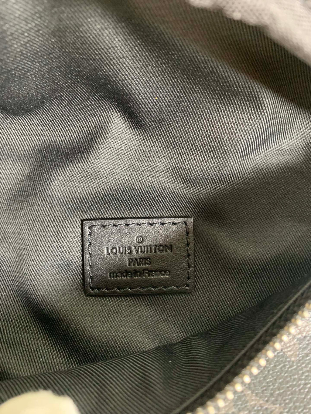 Black fabric inside label with Louis Vuitton branding on belt bag