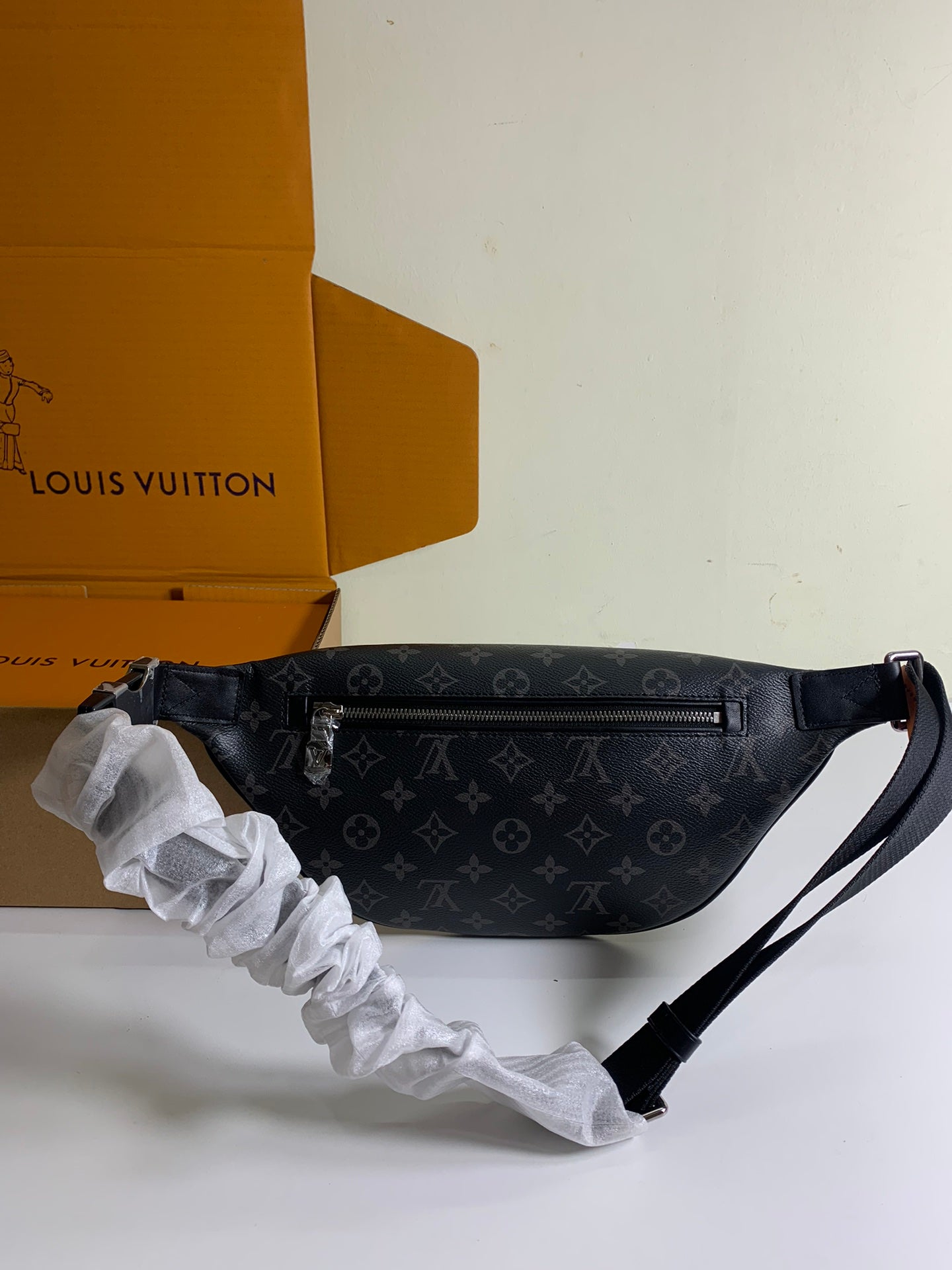 Black monogram belt bag on display with shoulder strap and front flap