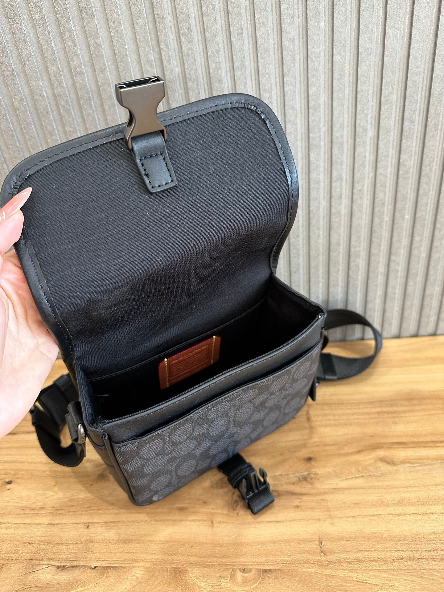 Coah bag open view; black top, patterned lower panel, buckle hardware, lined interior