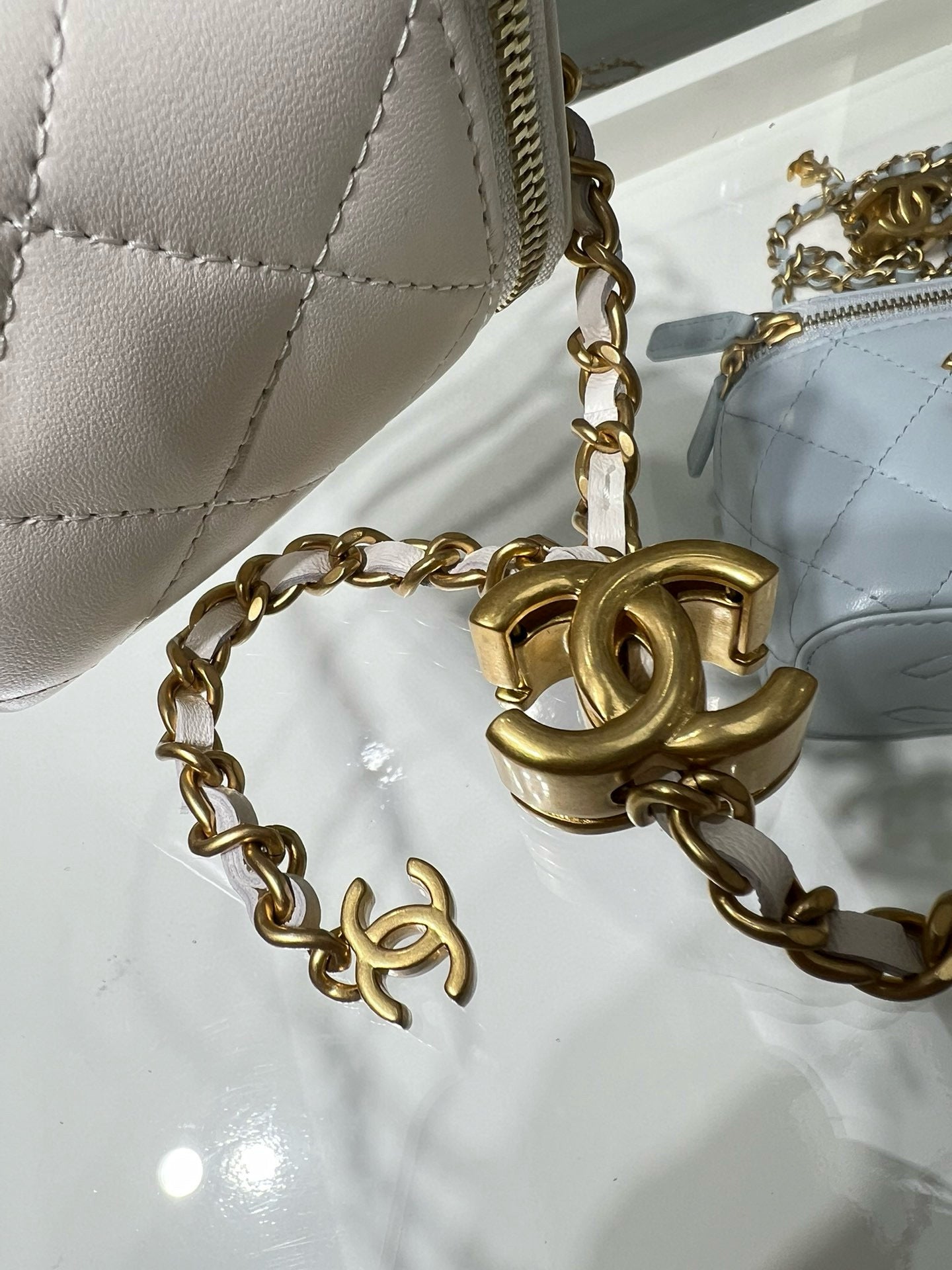 White quilted bag close-up of gold chain and large gold CC charm