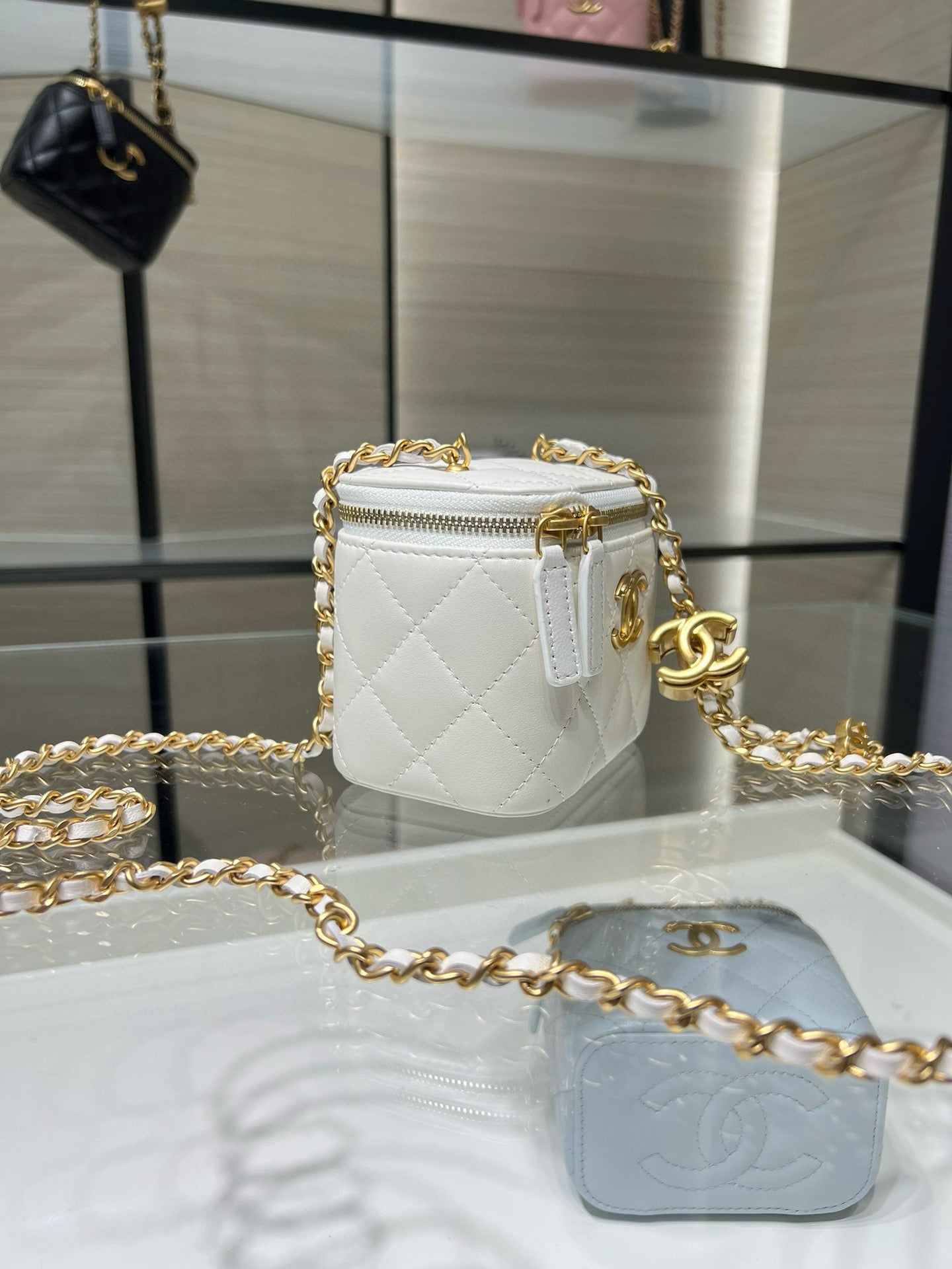 White quilted mini bag with gold chain, front CC logo, and zip closure.