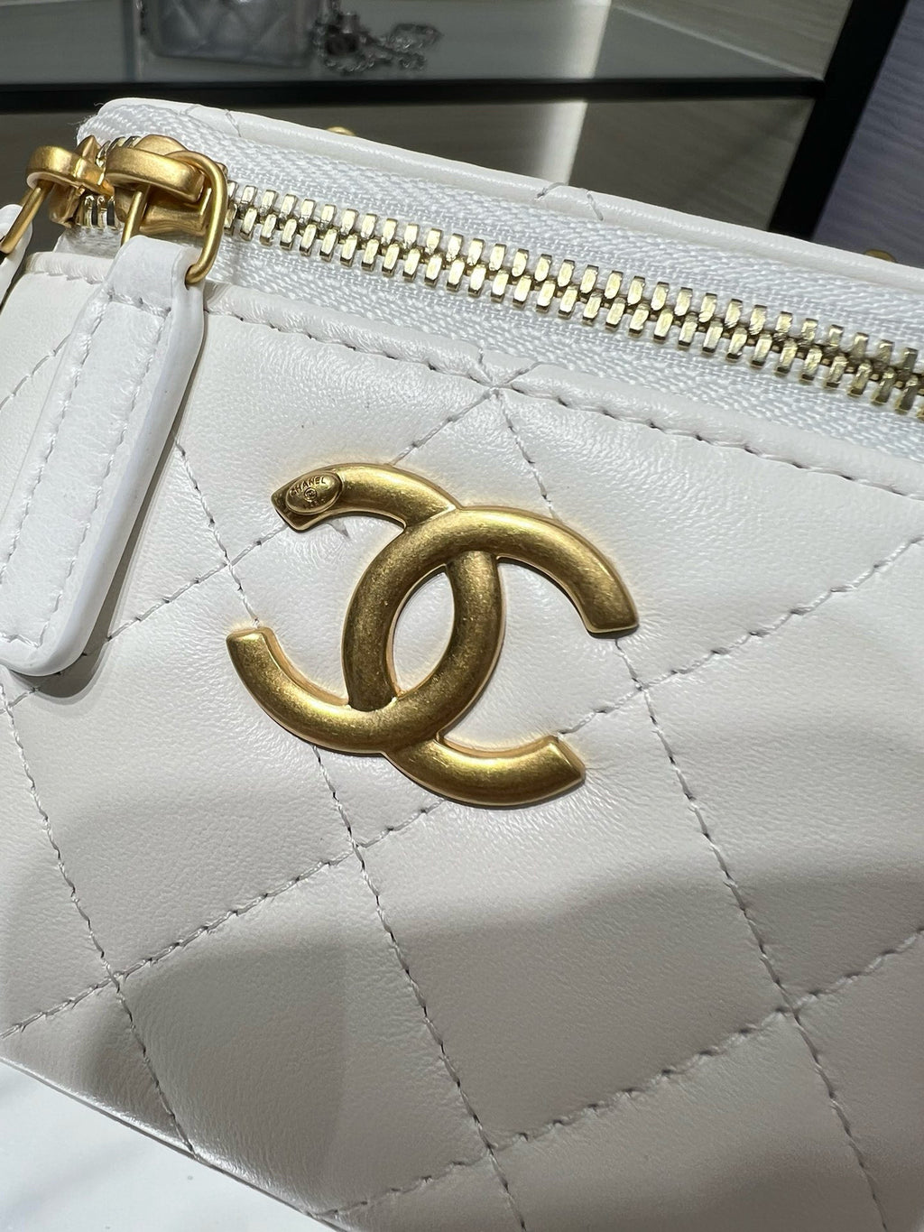 White quilted mini bag close-up with gold CC emblem and gold-tone zipper hardware.