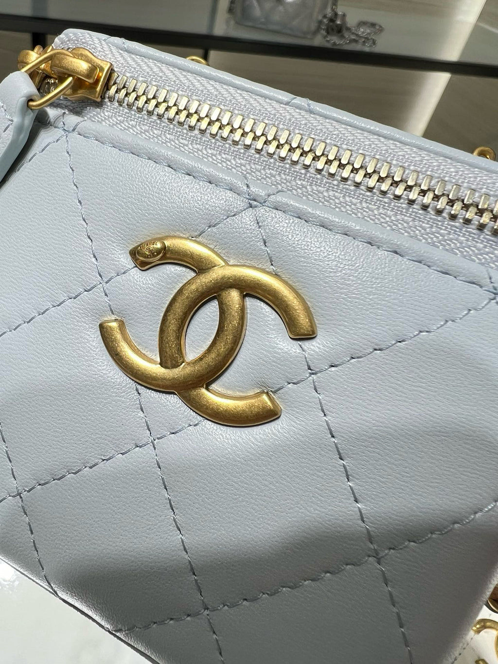 Chanel light blue quilted leather bag close-up of gold CC logo and zipper pull
