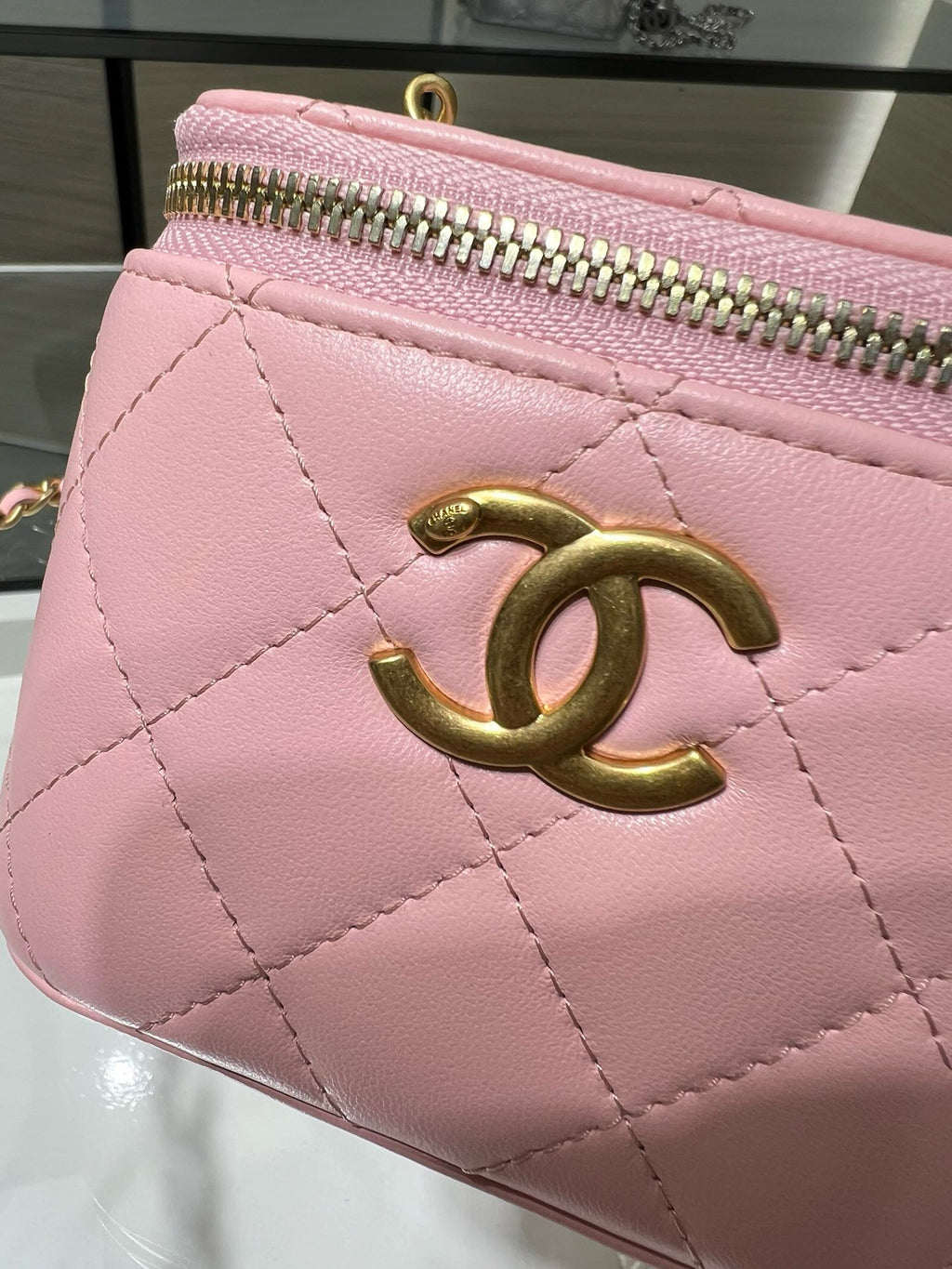 Pink Chanel mini bag with quilted design, gold CC emblem, and zip top.