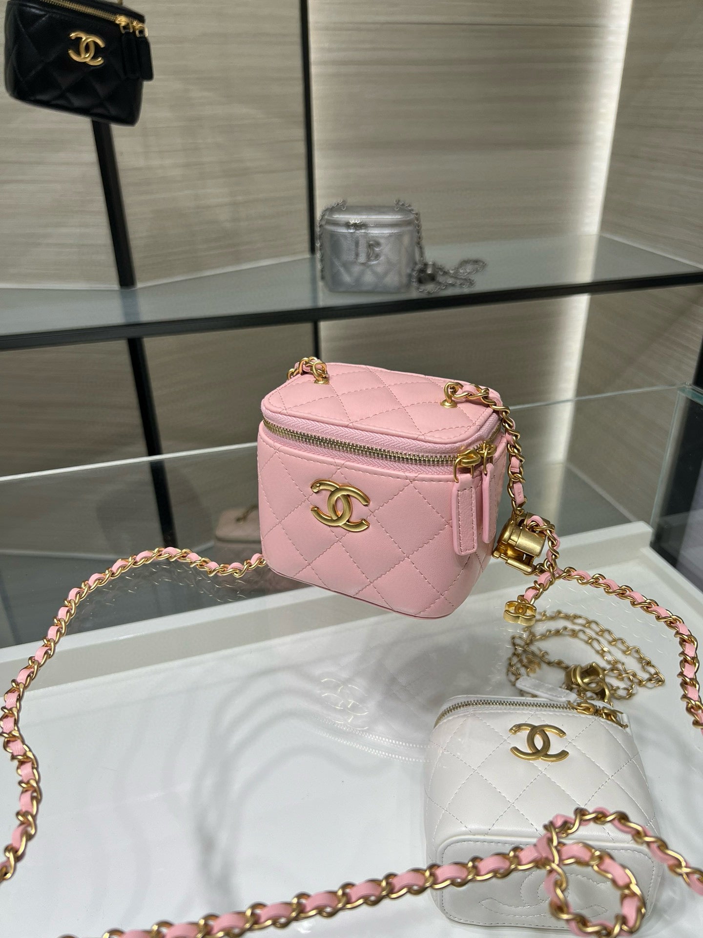 Pink Chanel cube-style mini bag with gold chain strap and front CC emblem.