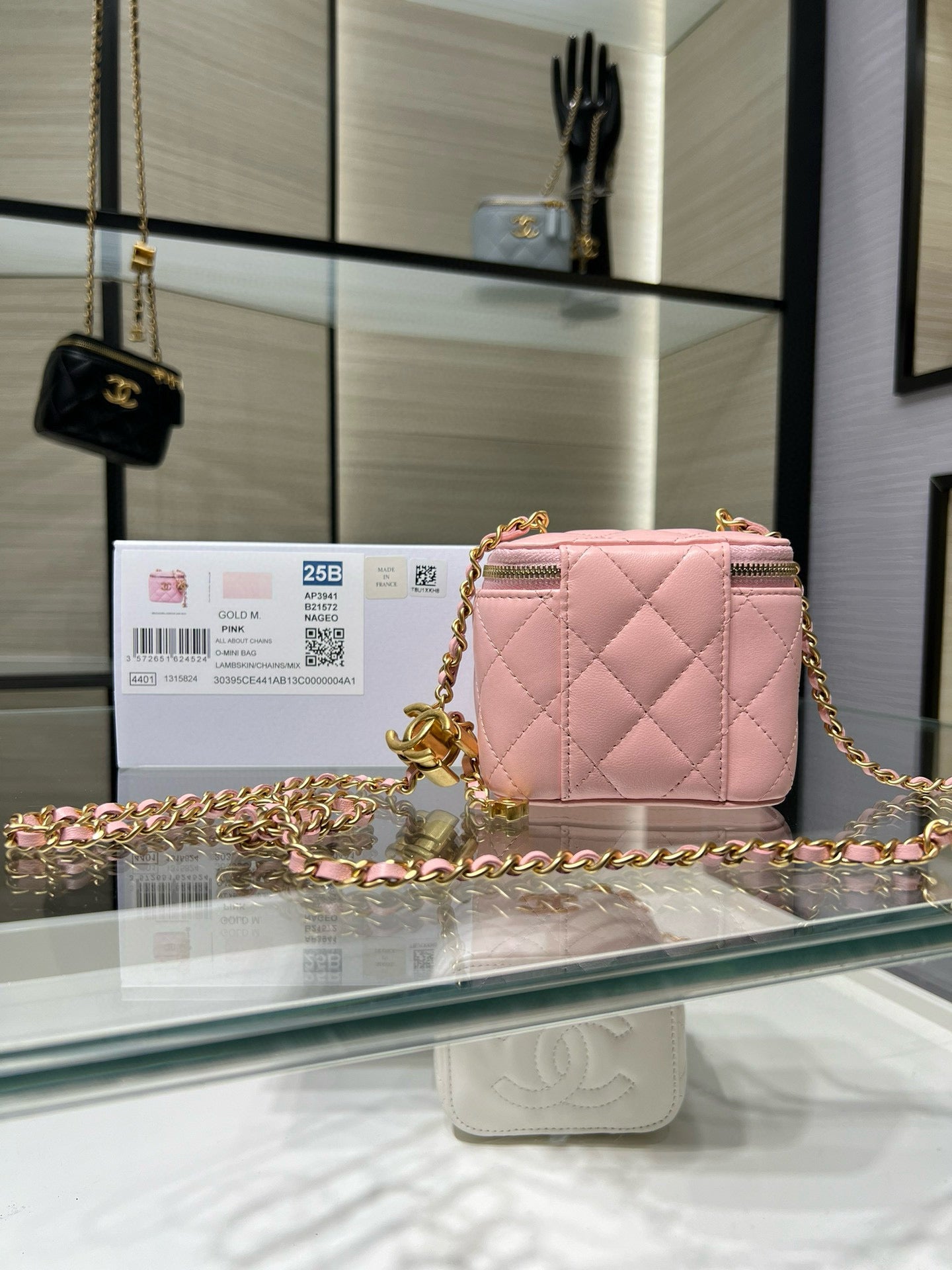 Pink quilted mini bag with gold chain crossbody strap and front zipper pocket.
