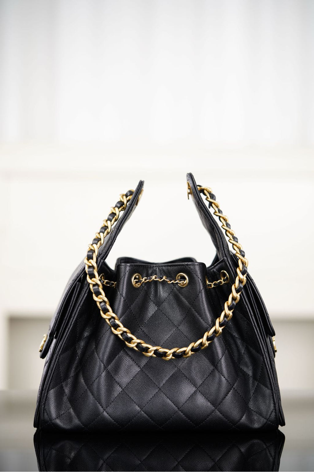 Black Chanel quilted bucket bag with double chain handles and gold hardware