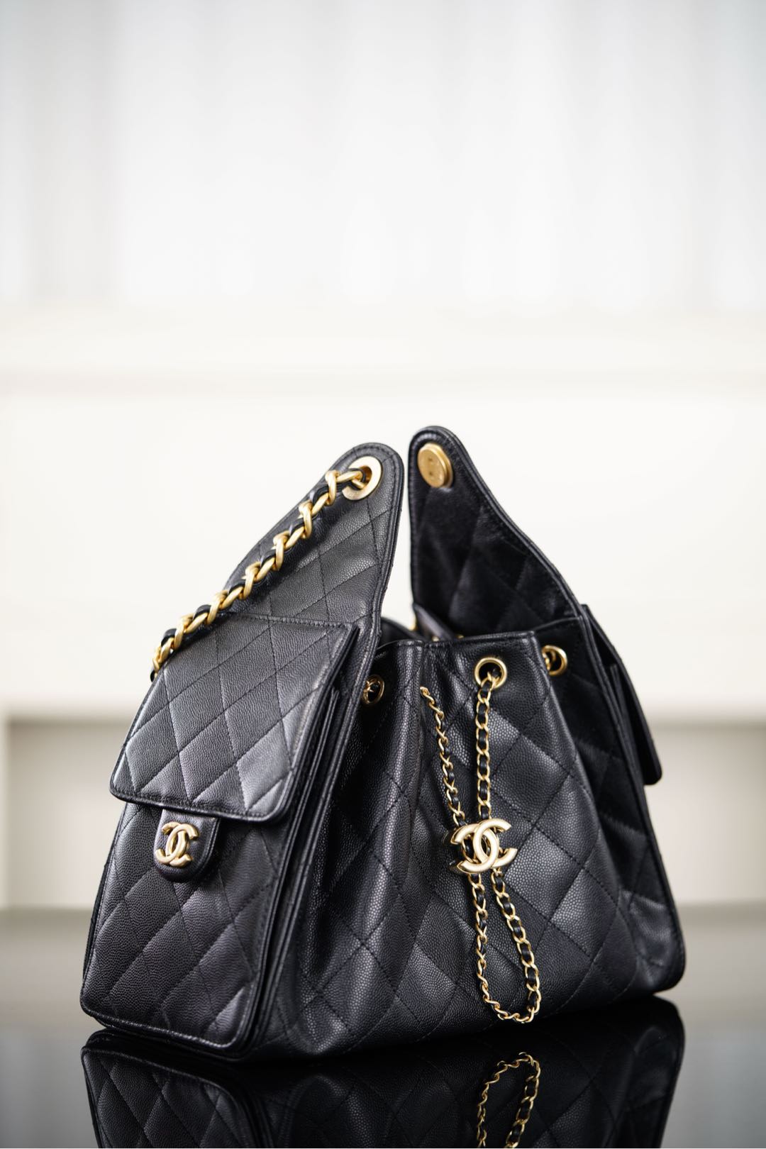 Black Chanel quilted bucket bag with side flap and gold chain strap