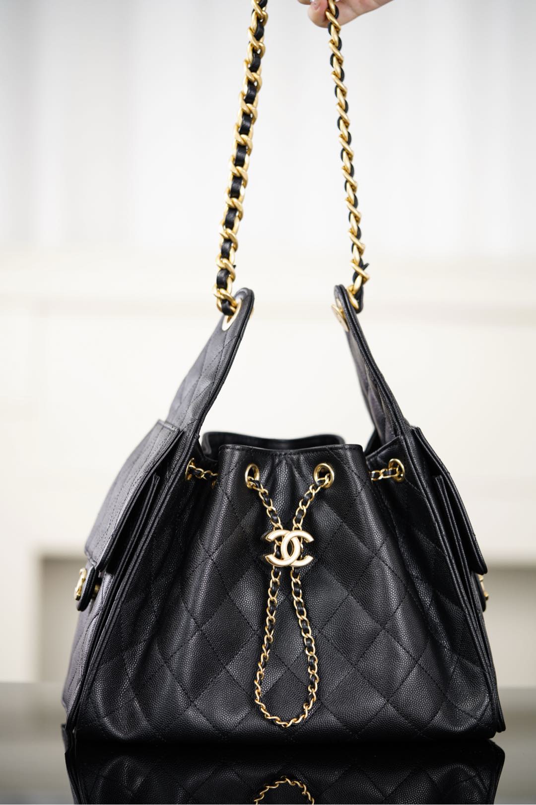 Black Chanel quilted bucket bag with long gold chain straps and CC logo