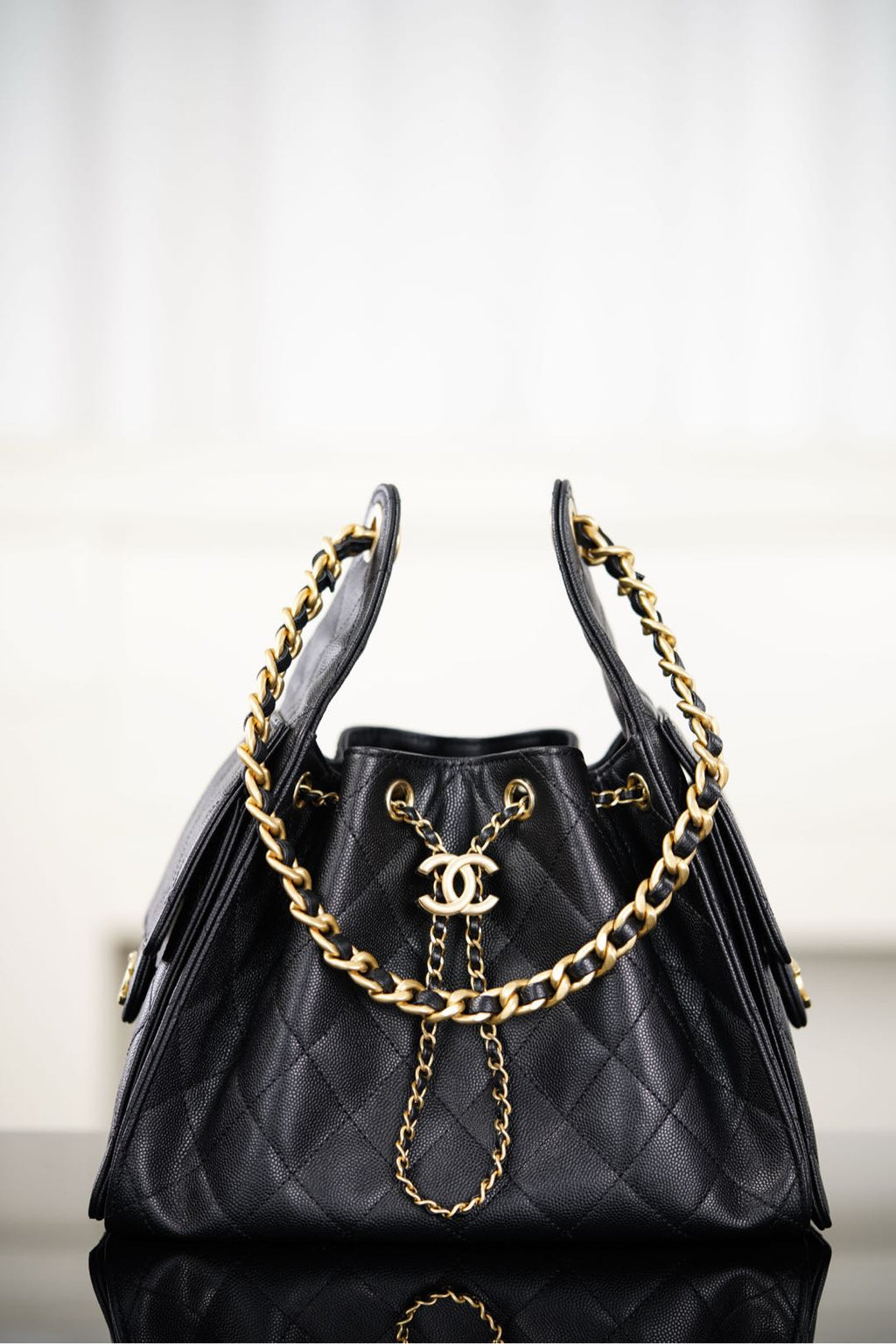 Black Chanel quilted bucket bag with gold chain straps and CC logo front
