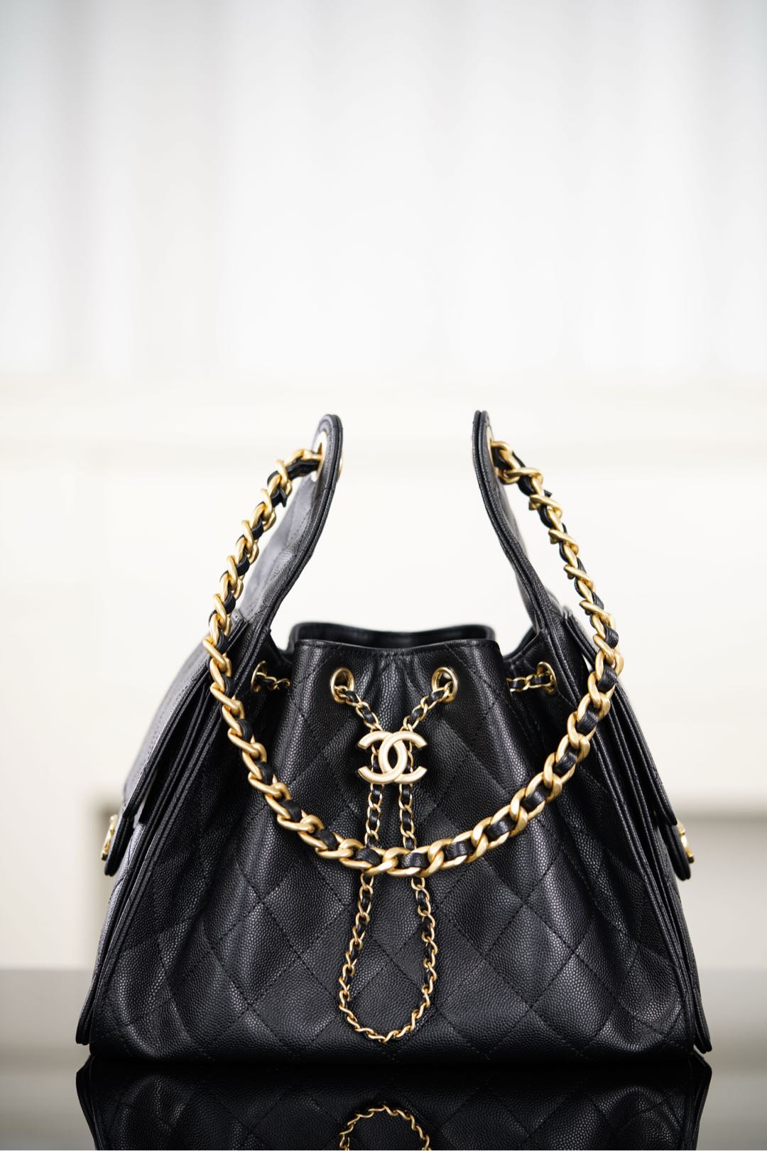 Black Chanel quilted bucket bag with gold chain straps and CC logo front