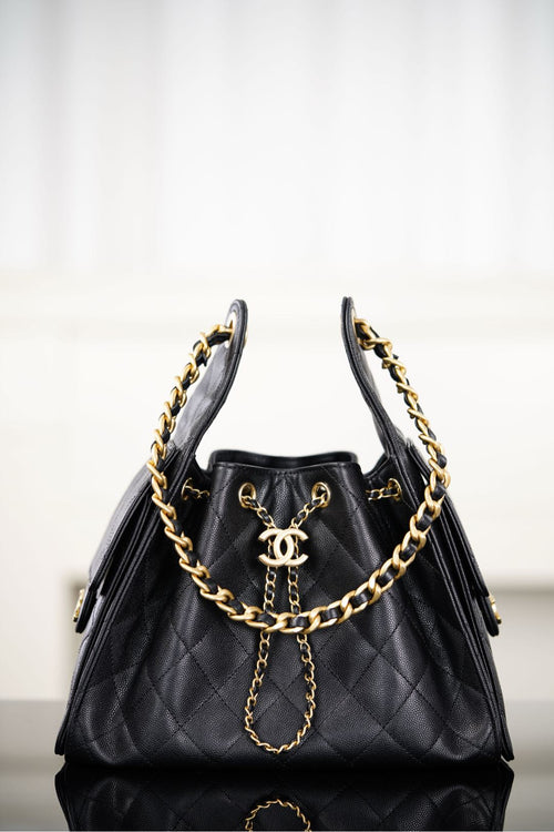 Black Chanel quilted bucket bag with gold chain straps and CC logo front