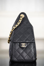 Black Chanel quilted flap bucket bag with gold chain strap and CC logo plate