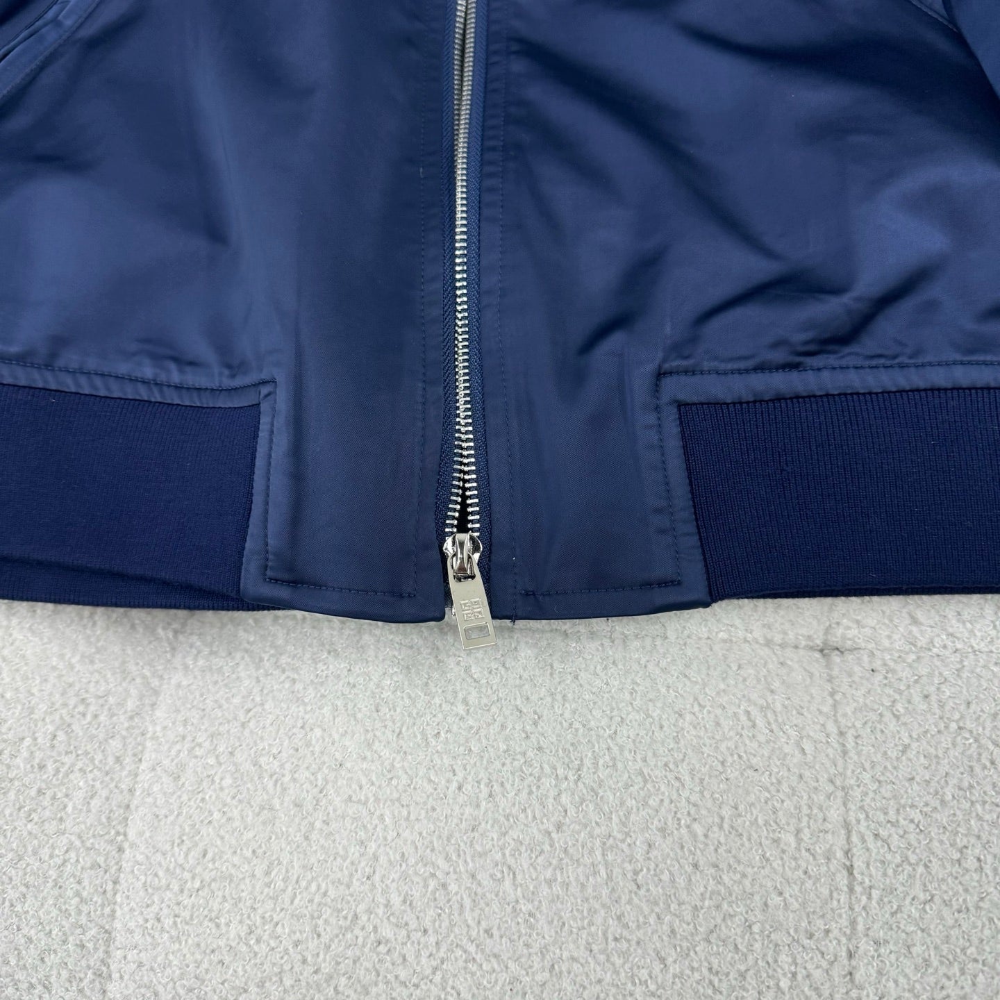Dark blue bomber jacket with front zip and side zip pockets plus ribbed hem