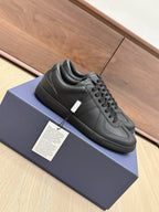 Black low-top sneakers with lace-up design, side panel seams, and small white tag
