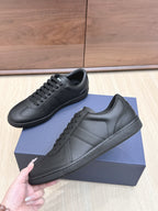 Black low-top leather sneakers with lace-up front, side stitching, and padded collar