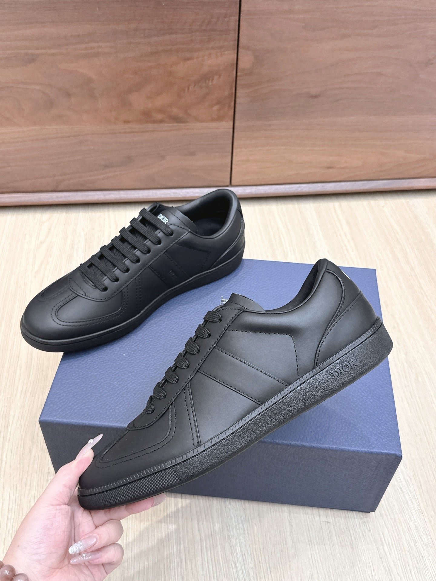 Black low-top leather sneakers with lace-up front, side stitching, and padded collar
