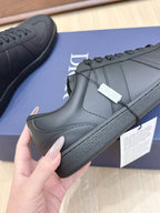 Dark leather sneaker with lace-up front, stitched side panels, and Dior on heel