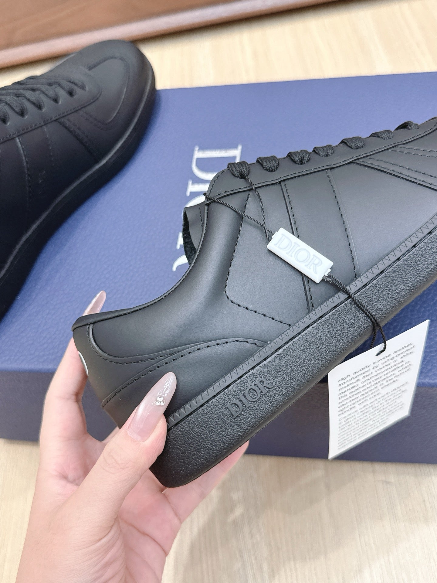 Dark leather sneaker with lace-up front, stitched side panels, and Dior on heel