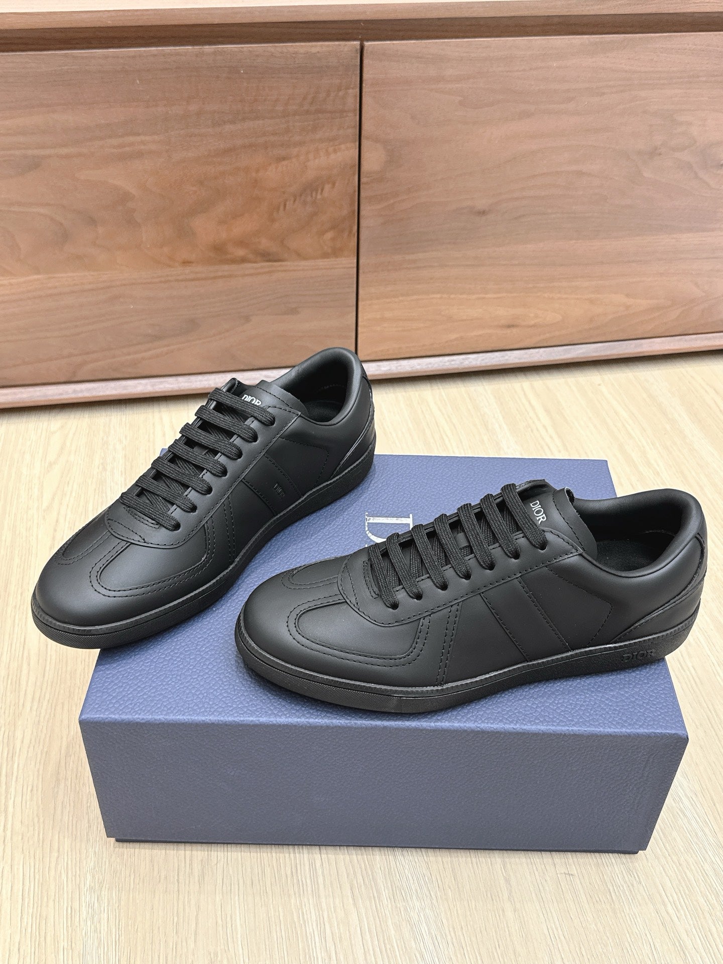 Dark leather low-top sneakers pair with black laces and Dior logo patches