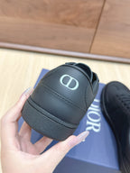 Black low-top sneakers with rounded toe, padded collar, and Dior logo on side