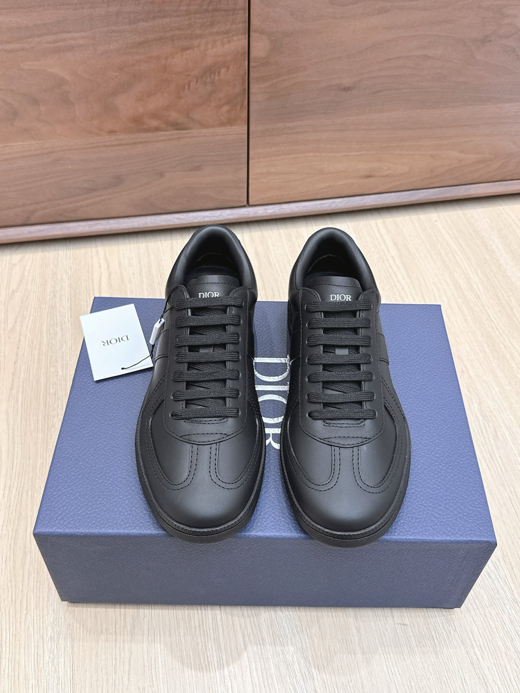 Black low-top leather sneakers with lace-up front and Dior logo on tongue