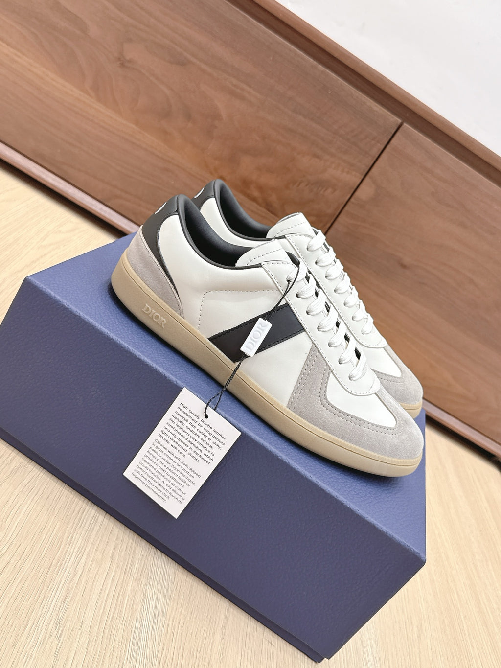 Side view of white, gray, and black lace-up sneakers with beige rubber sole.