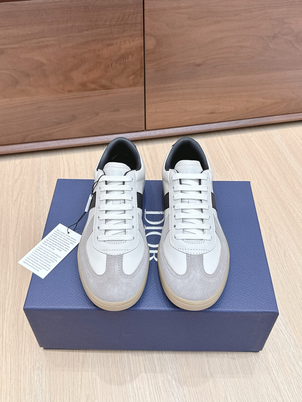 White and gray lace-up sneakers with black accents, placed on a blue shoe box.