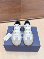 White and gray lace-up sneakers with black accents, placed on a blue shoe box.