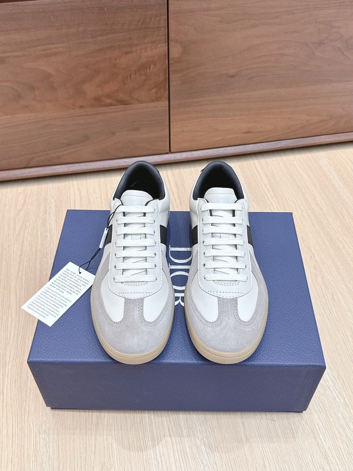 White and gray lace-up sneakers with black accents, placed on a blue shoe box.