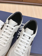 Two white lace-up sneakers with black lining and “Dior” label inside heel.
