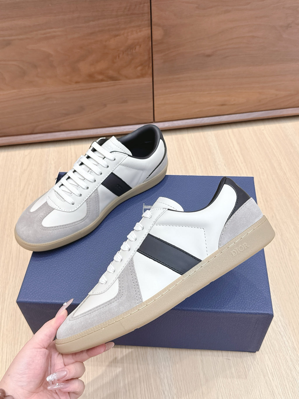 White and gray lace-up sneakers with black stripe and beige sole detail.